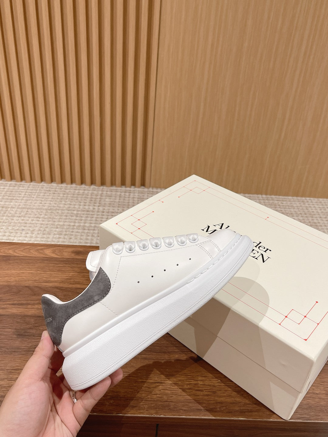 White leather low-top sneakers with gray suede heel and lace-up front, thick sole