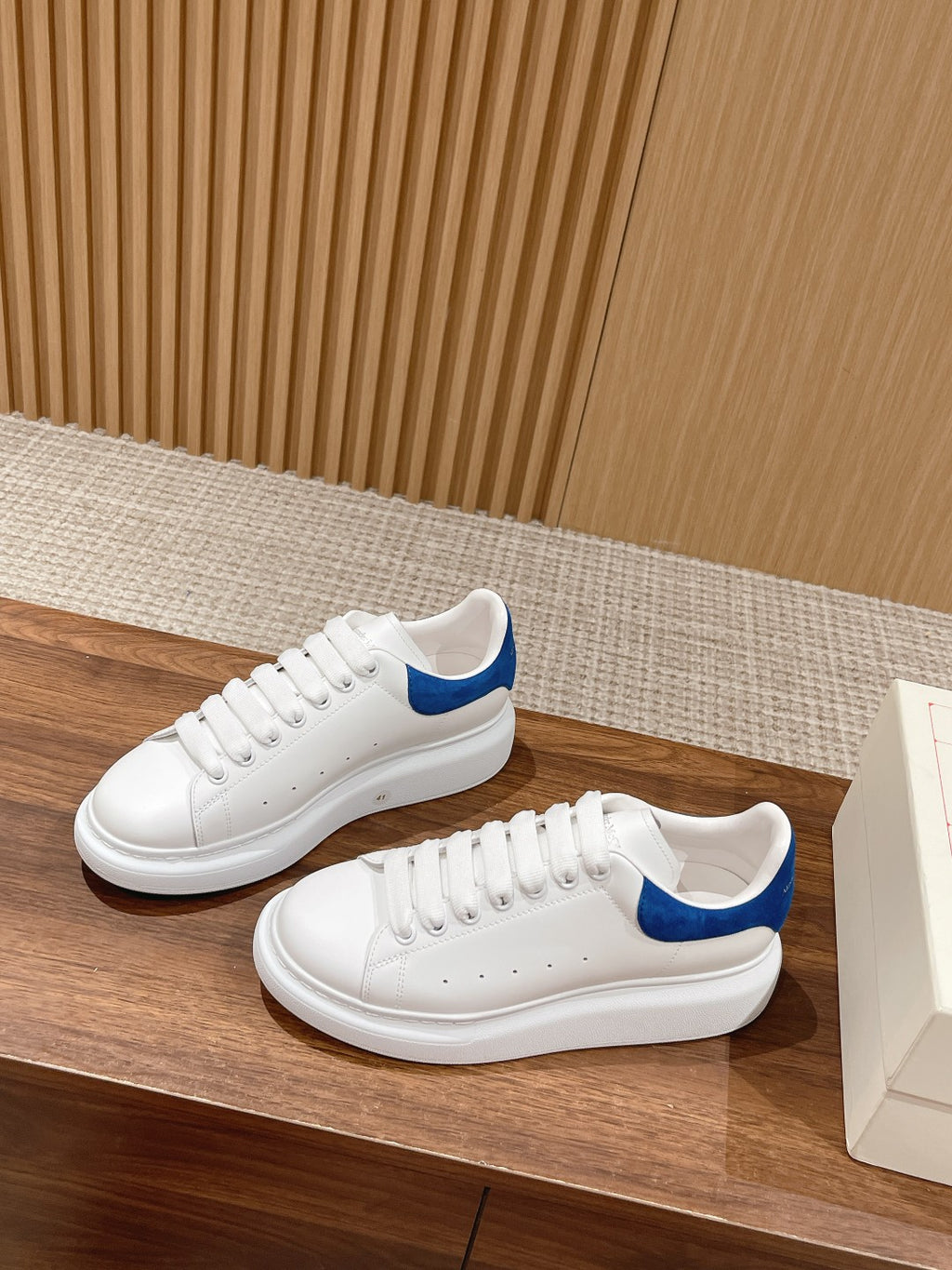 White low-top sneakers with blue-trim collar and perforated toe