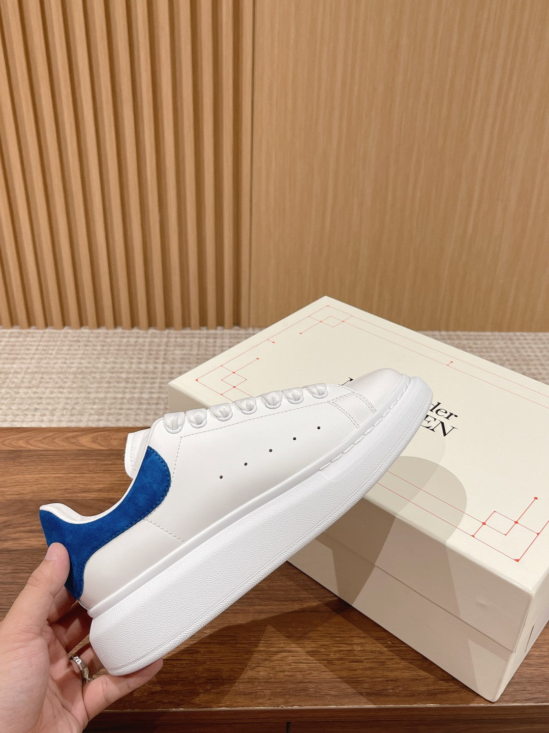 White low-top leather sneakers with blue suede heel tab and perforated toe
