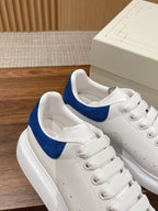 White leather sneakers with blue suede collar and lace-up design, side view