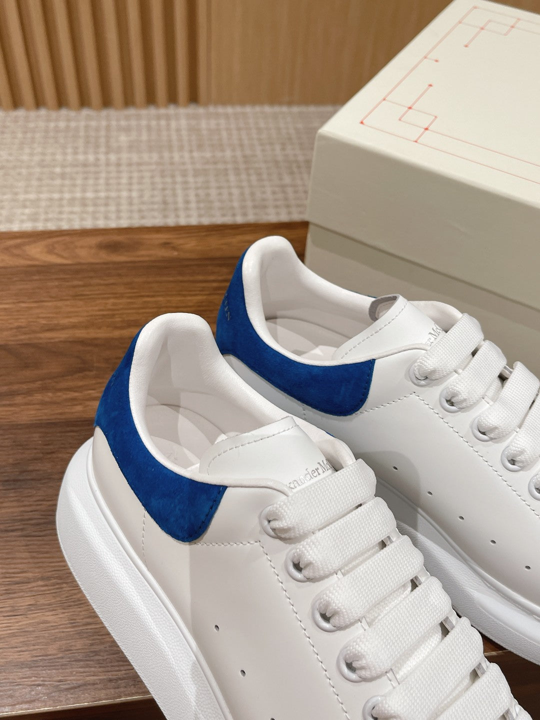 White leather sneakers with blue suede collar and lace-up design, side view