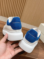 White low-top sneakers with blue heel panels and cushioned collar, heel view