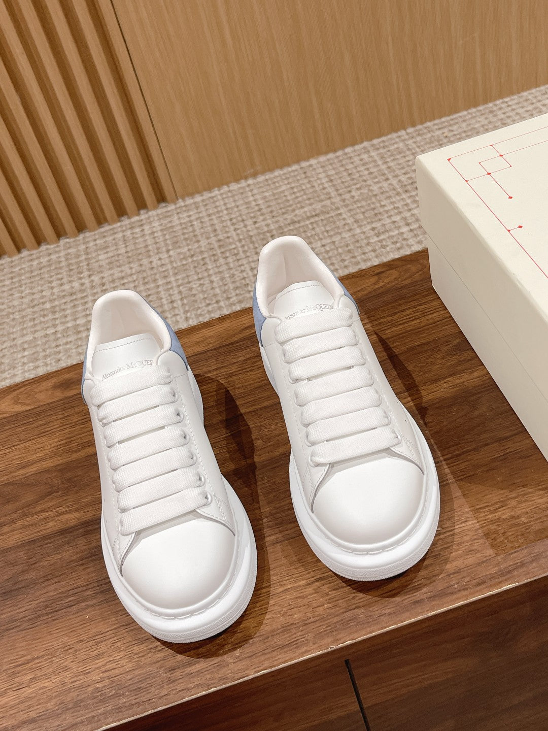 Pair of white leather lace-up sneakers with light blue heel panels and white rubber soles
