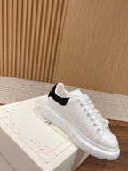 Alexander McQueen white low-top sneakers with black heel insert and round toe