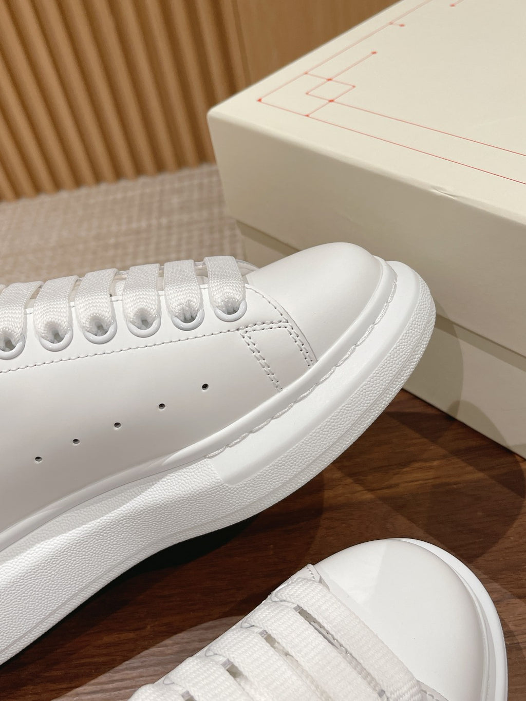 Alexander McQueen white sneaker close-up with black heel tab and textured sole