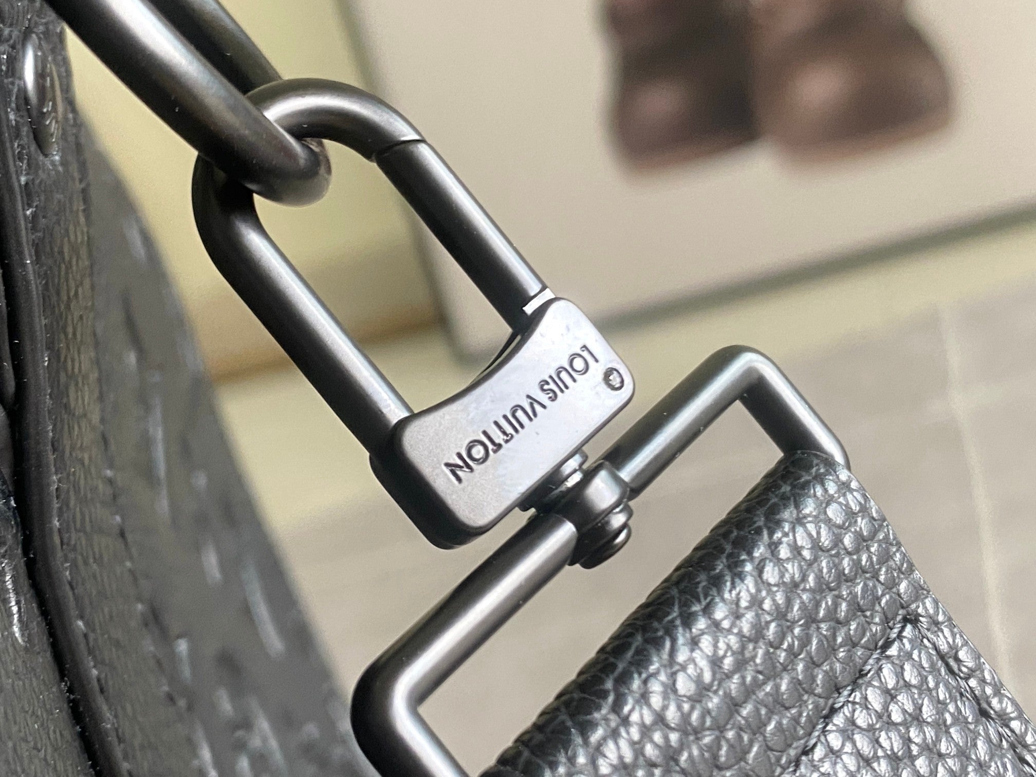 Louis Vuitton duffel bag handle hardware on dark textured leather