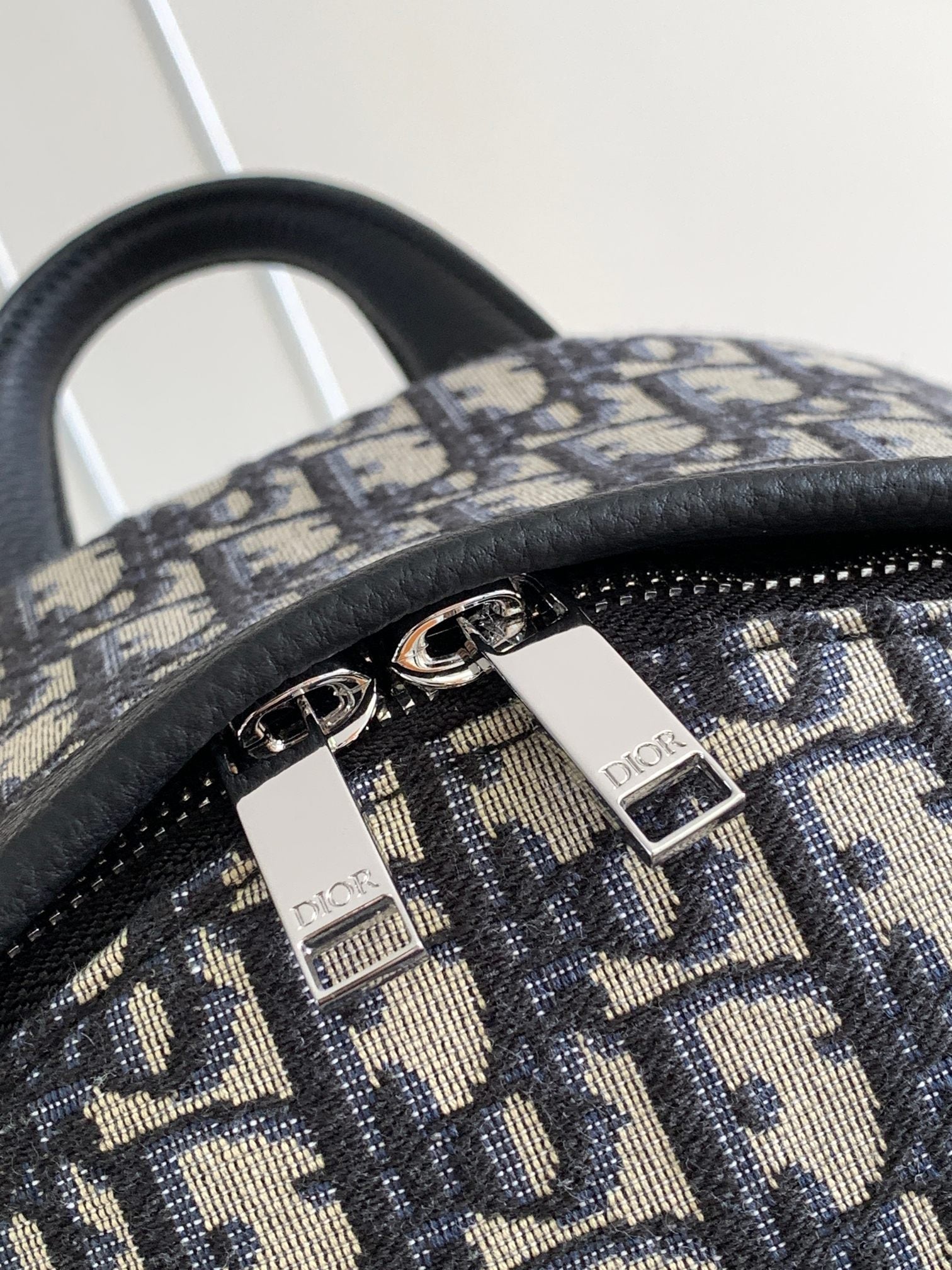 Dior monogram backpack bag hardware with two zipper sliders on patterned canvas