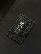 Dior logo leather patch on black interior lining of a men's Dior bag