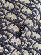 Men's Dior backpack flap showing textured Oblique pattern and metal clasp rings