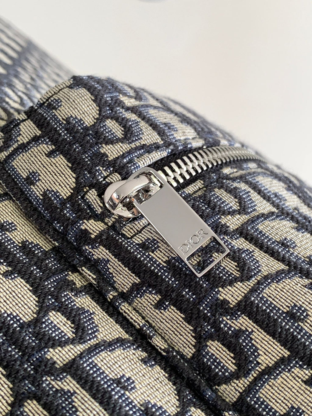 Men's Dior backpack zipper pull with Dior logo on patterned canvas