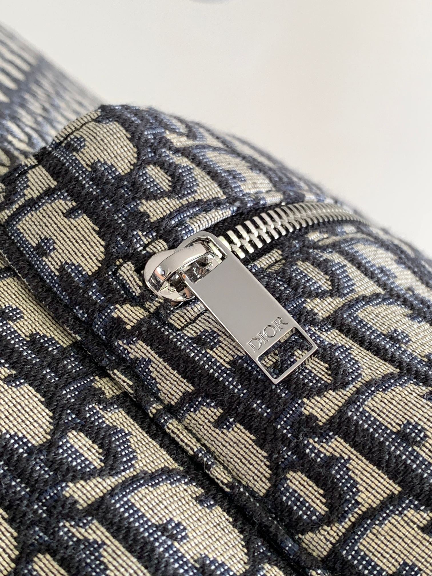 Men's Dior backpack zipper pull with Dior logo on patterned canvas