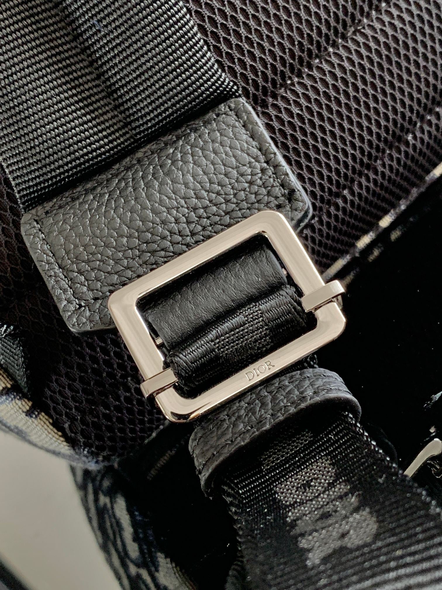 Men's Dior backpack strap hardware with metal buckle and black leather detail