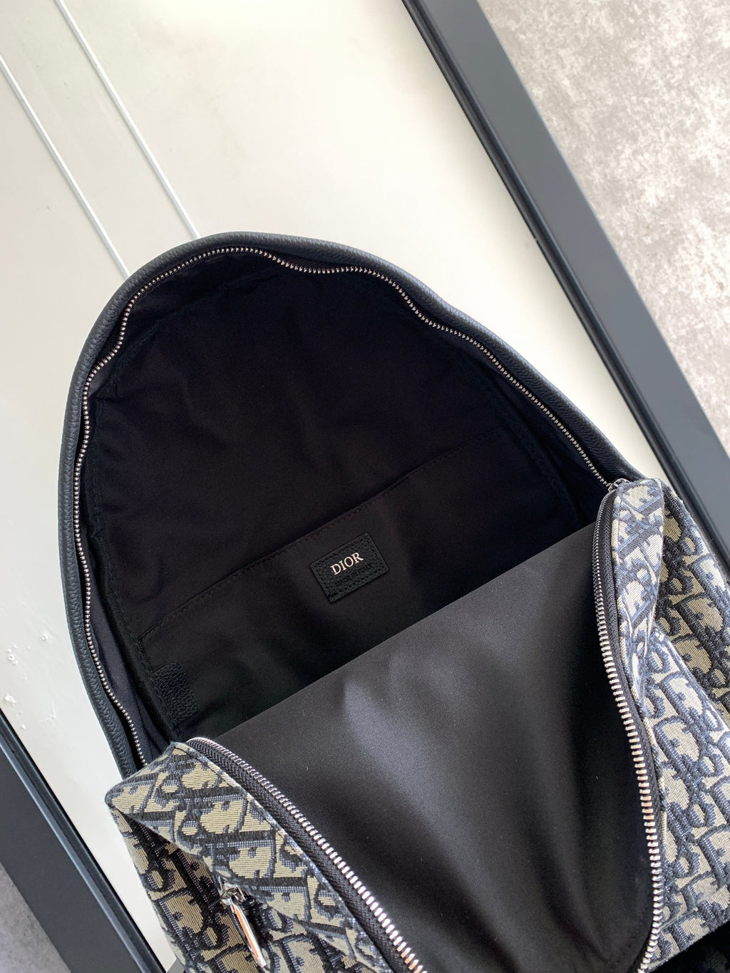 Men's Dior backpack open top with black fabric lining and patterned inner panel