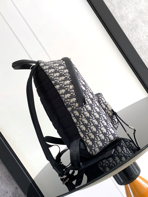 Dior men's mini backpack side view with blue-and-cream monogram fabric and adjustable straps