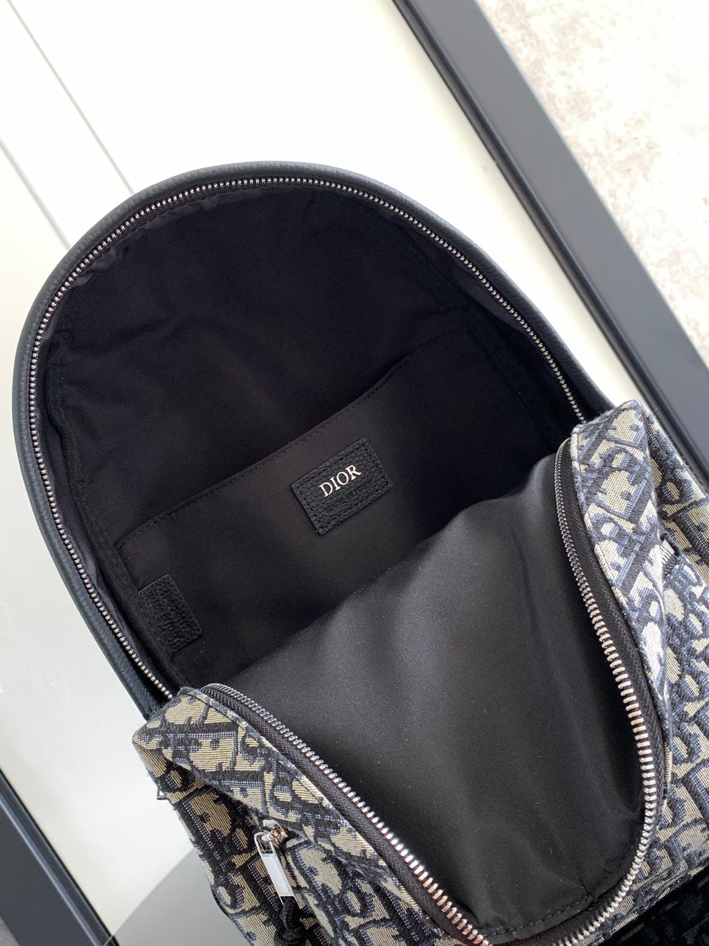 Dior men's mini backpack open interior with black lining and zippered main compartment