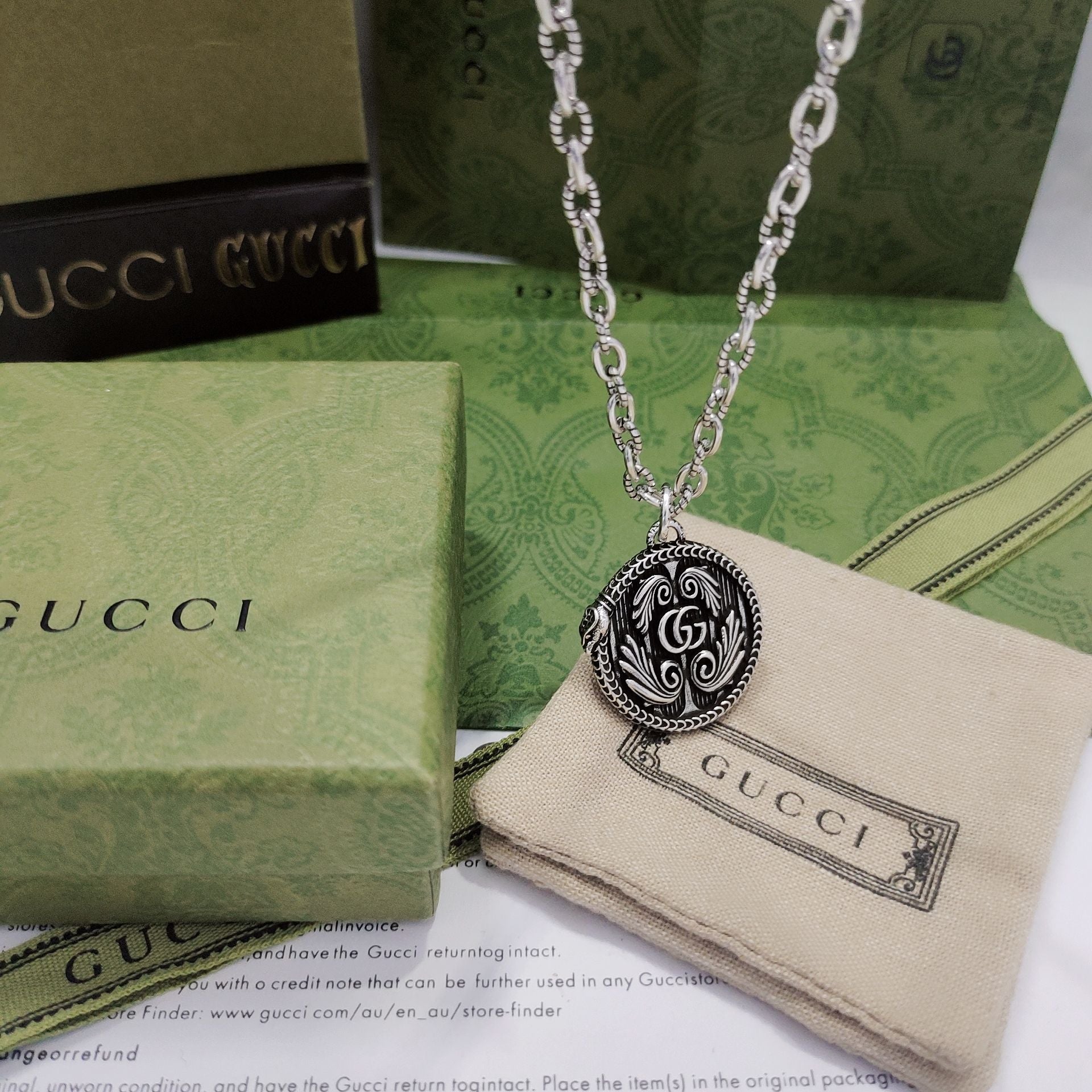 Silver-tone pendant necklace with round logo medallion and engraved swirl pattern