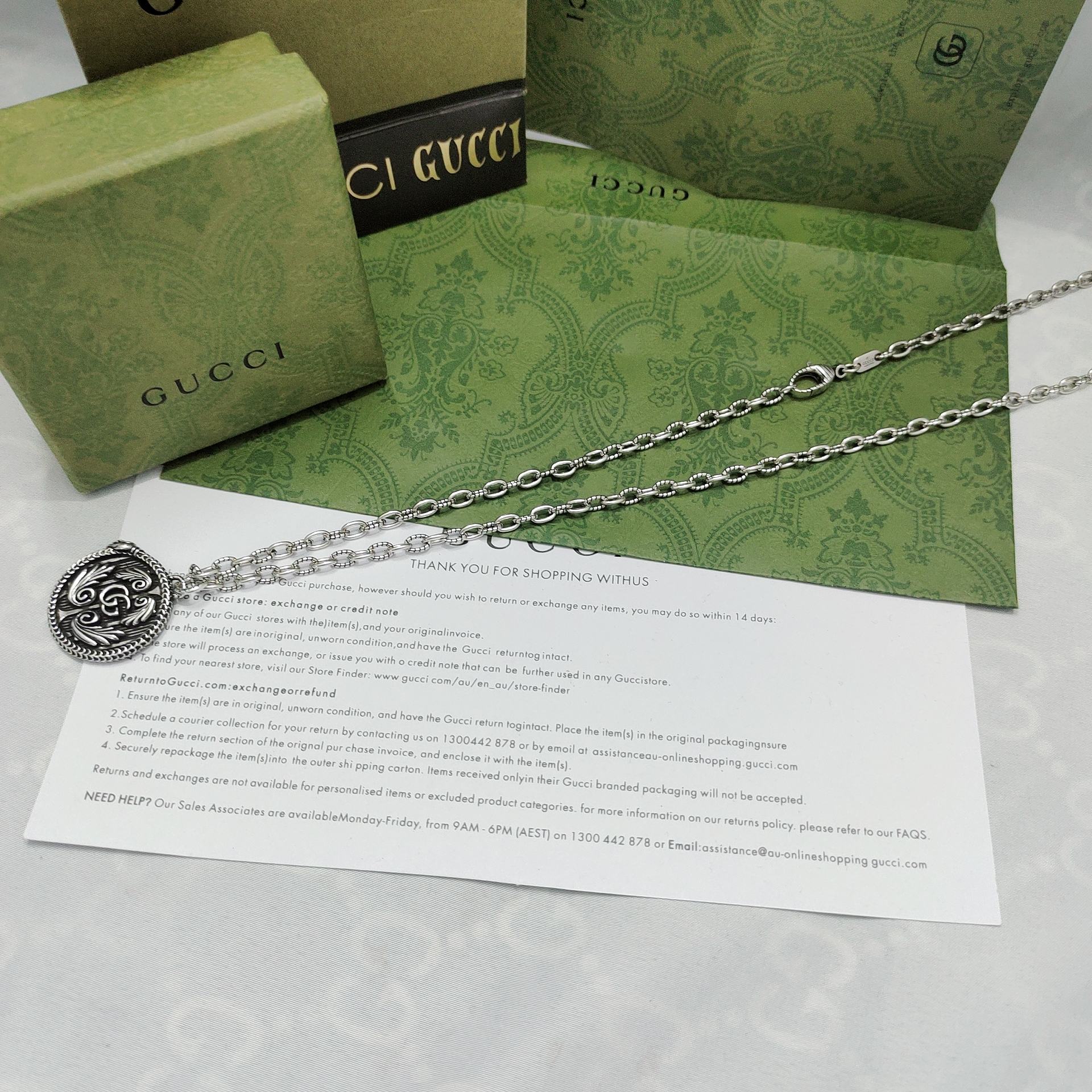 Silver-tone pendant necklace with round logo medallion on a long chain