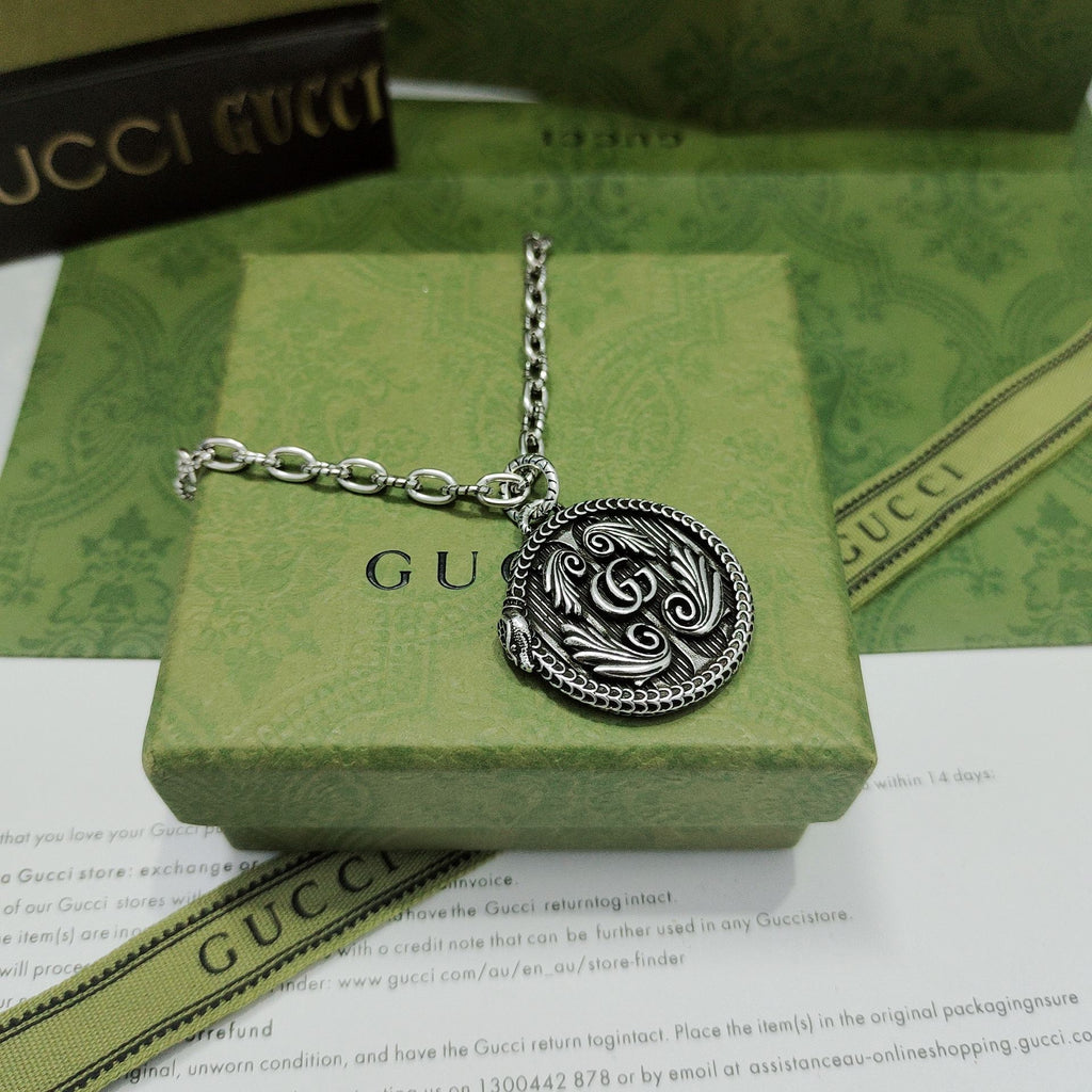 Silver-tone round logo pendant necklace with engraved swirl center