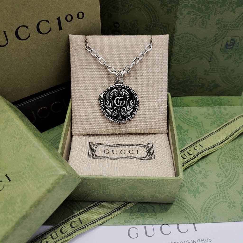 Silver-tone round logo pendant necklace with engraved swirl medallion