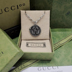 Silver-tone round logo pendant necklace with engraved swirl medallion