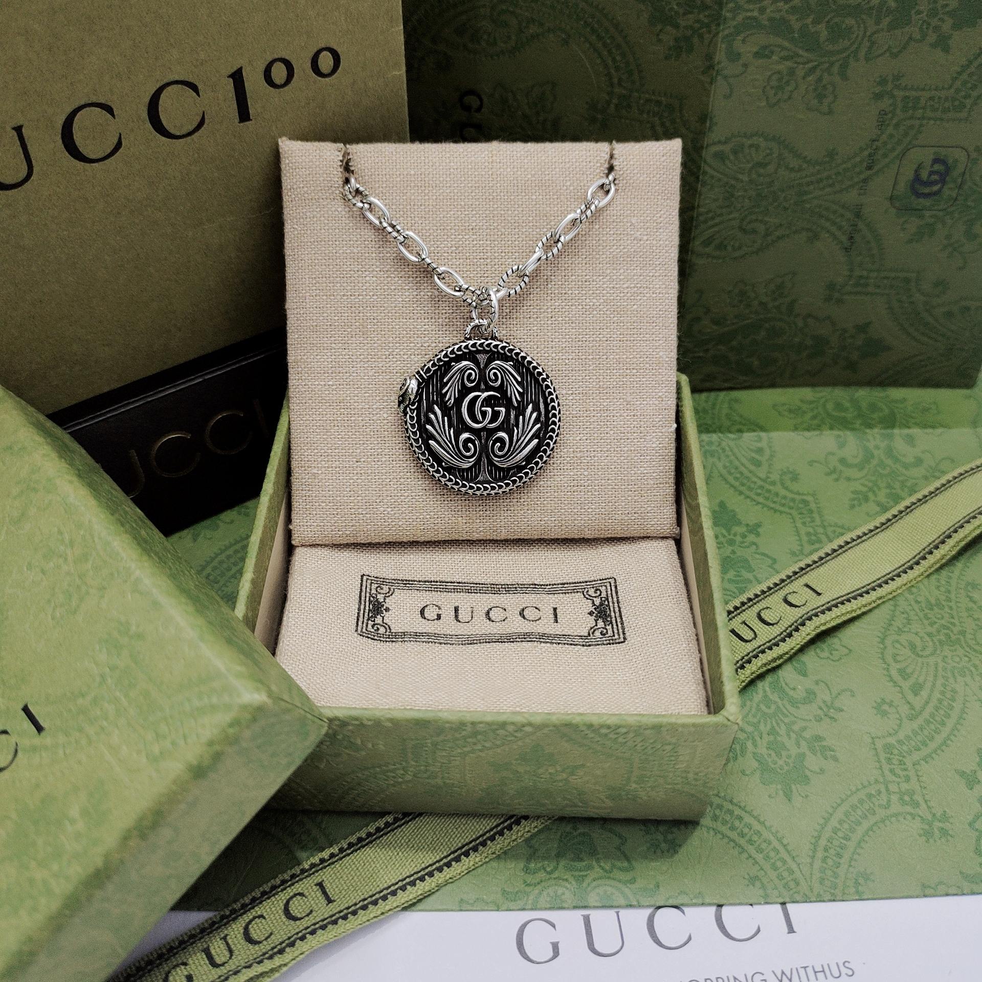 Silver-tone round logo pendant necklace with engraved swirl medallion
