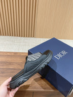 Dior monogram slide sandals, black patterned upper, hand holding shoe on Dior box