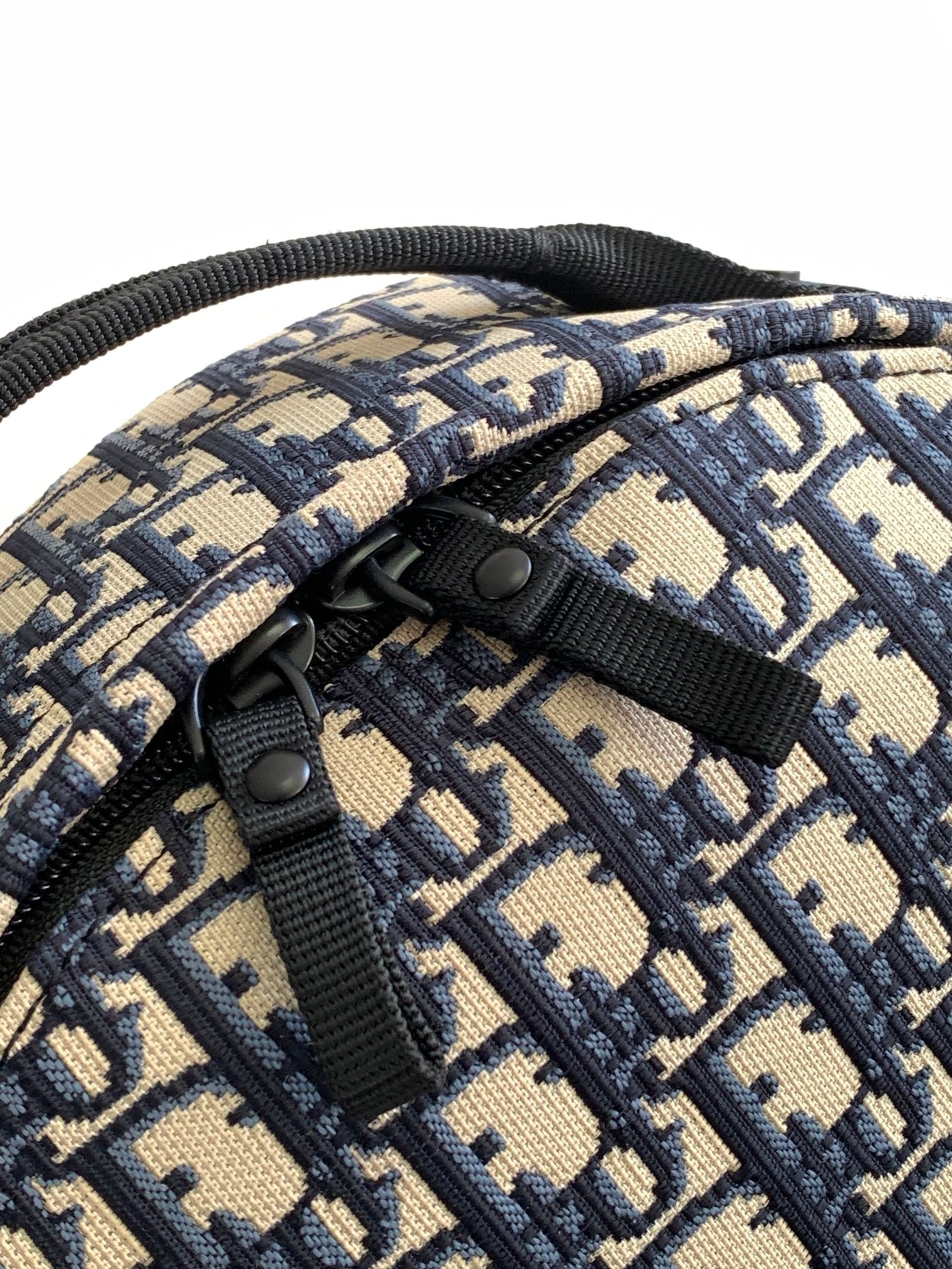 Dior monogram backpack detail showing black button and top handle strap