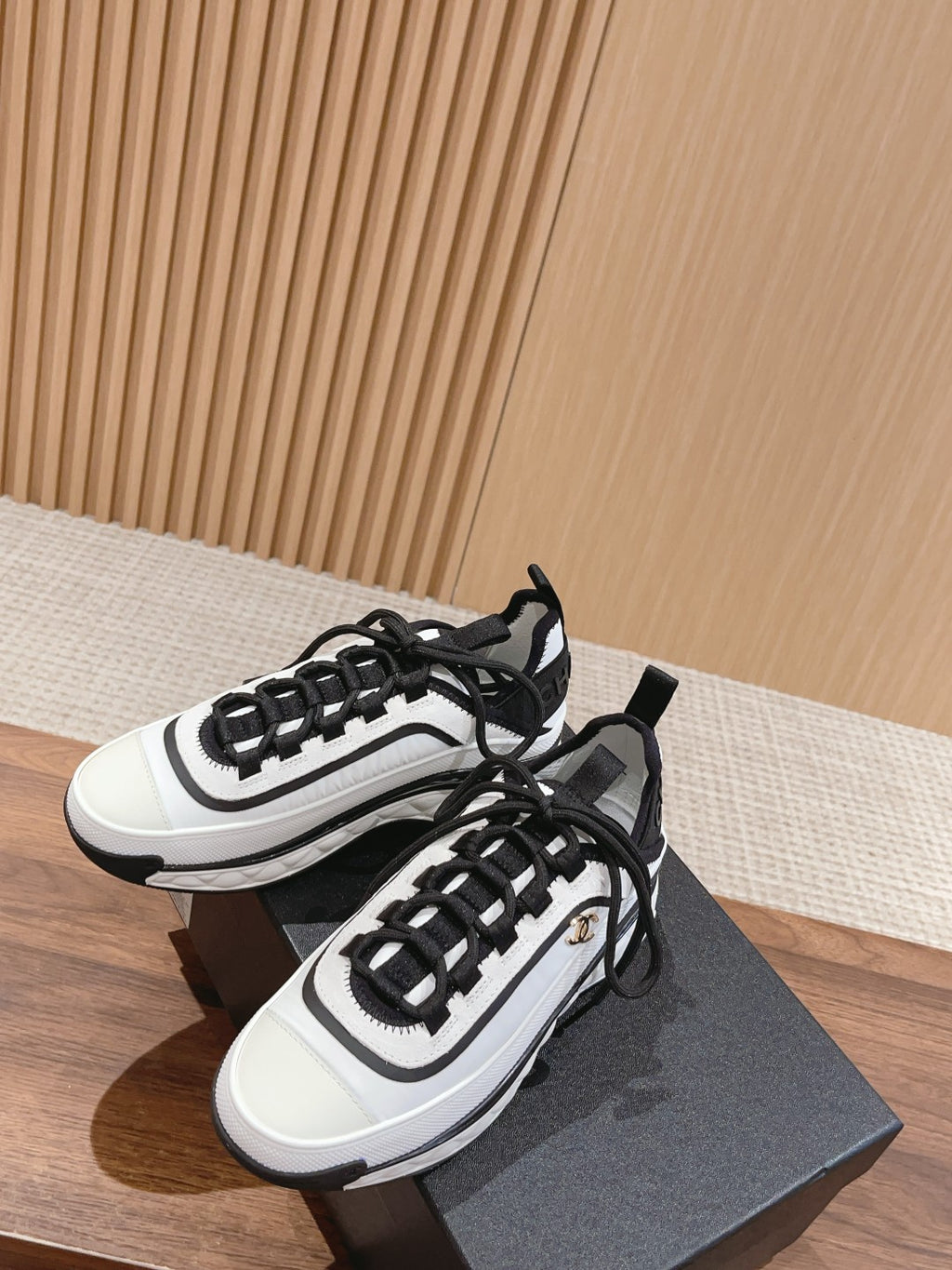Pair of white and black unisex sneakers on a dark box, lace-up style