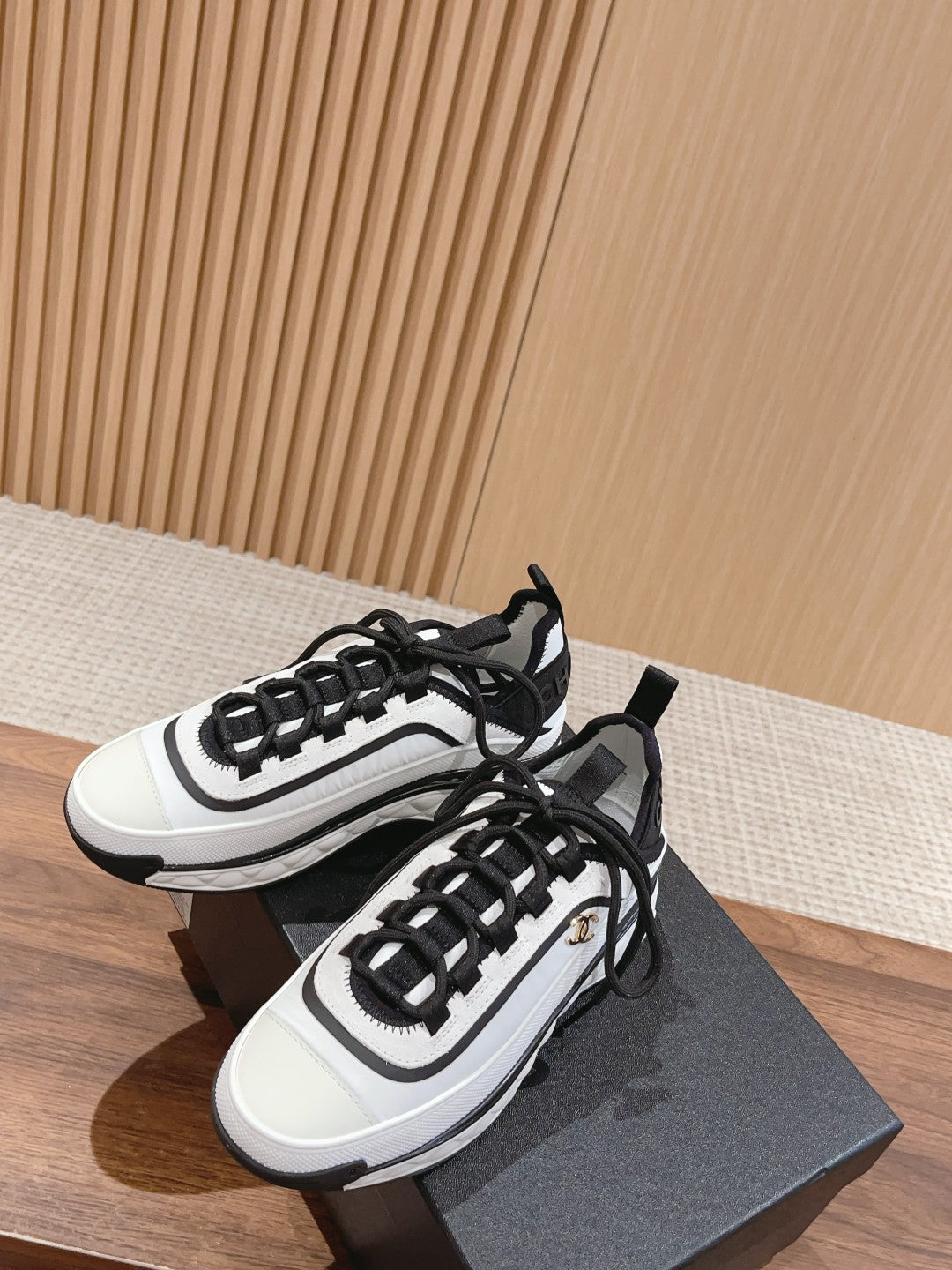 Pair of white and black unisex sneakers on a dark box, lace-up style