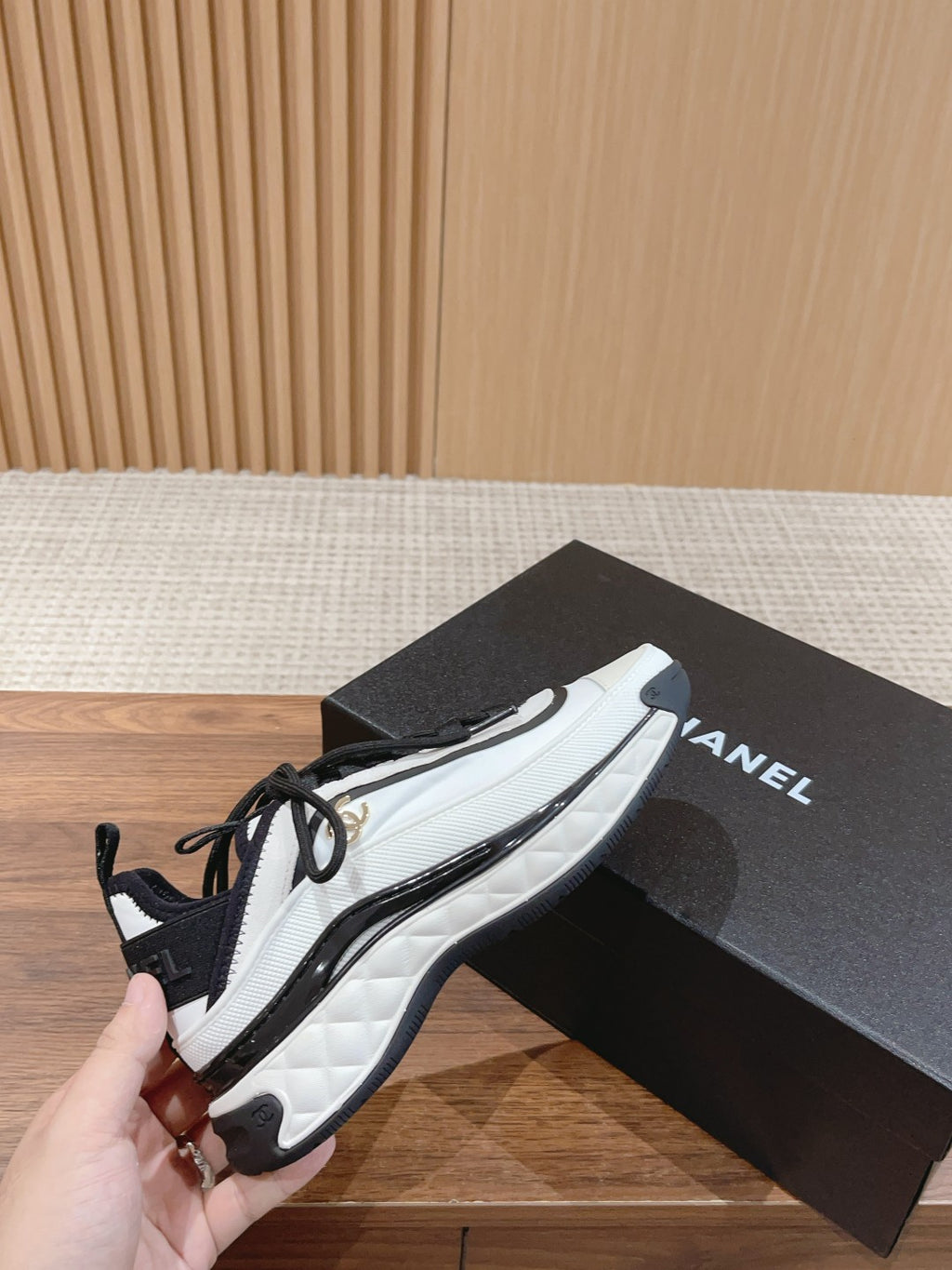 White and black unisex sneakers held in hand, lace-up with cushioned sole