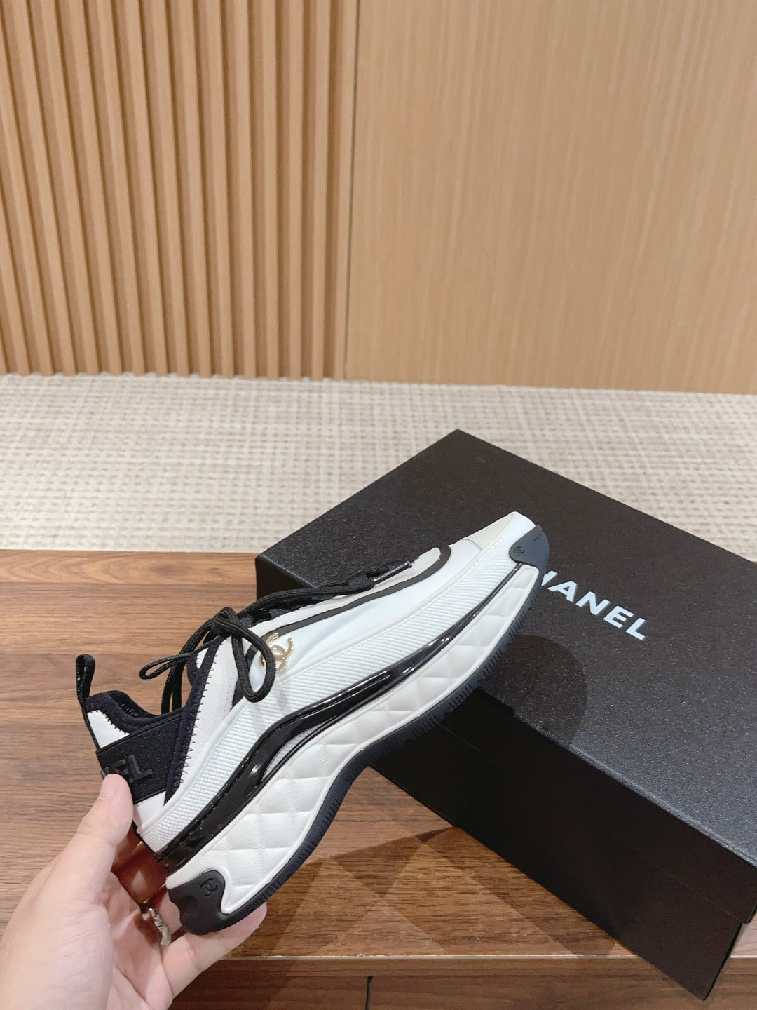 White and black unisex sneakers held in hand, lace-up with cushioned sole