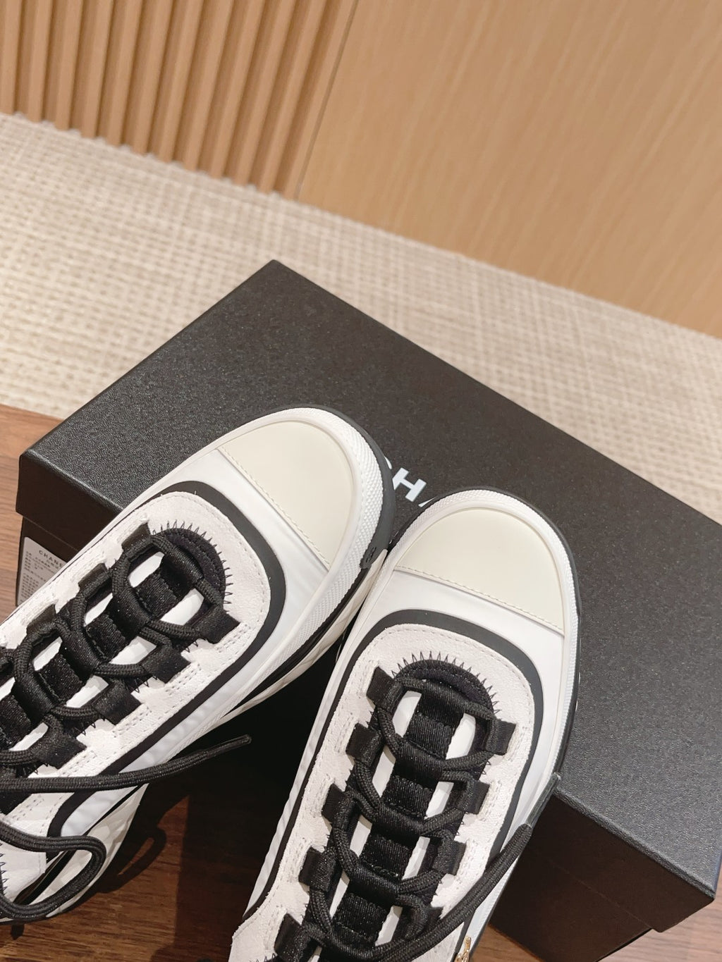 White and black unisex sneakers close-up with black laces and logo on tongue