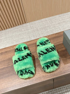 Mint green faux-fur slide sandals with black Balenciaga-style lettering, pair on floor.