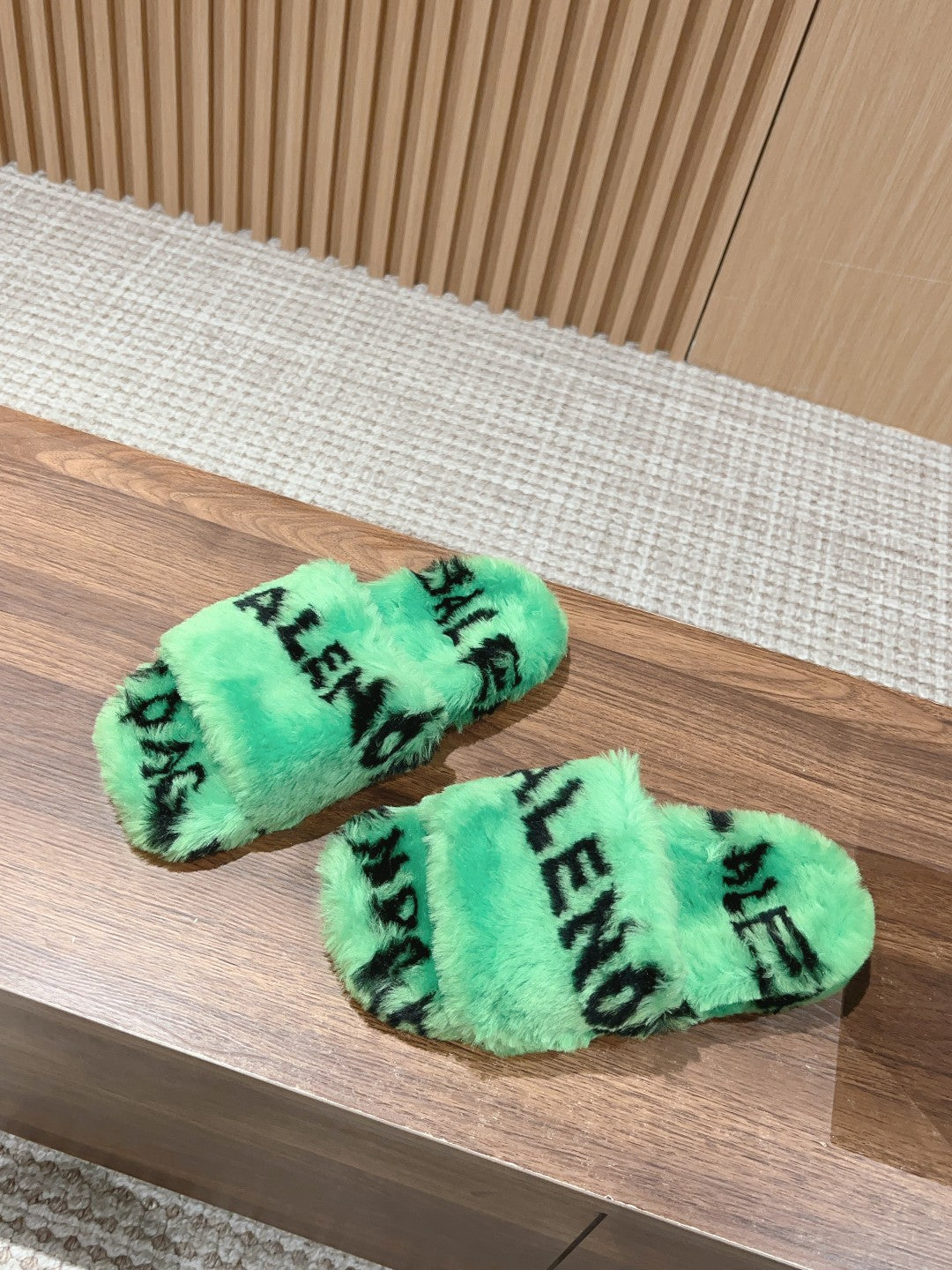 Mint green faux-fur slide sandals with black lettering, one sandal side view.
