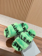 Mint green faux-fur slide sandals with black lettering, crossed pair on shoebox.
