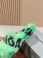 Mint green faux-fur slide sandal with black lettering, single pair resting on box.