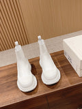 Pair of white Chelsea boots with elastic panels and thick, ridged rubber sole