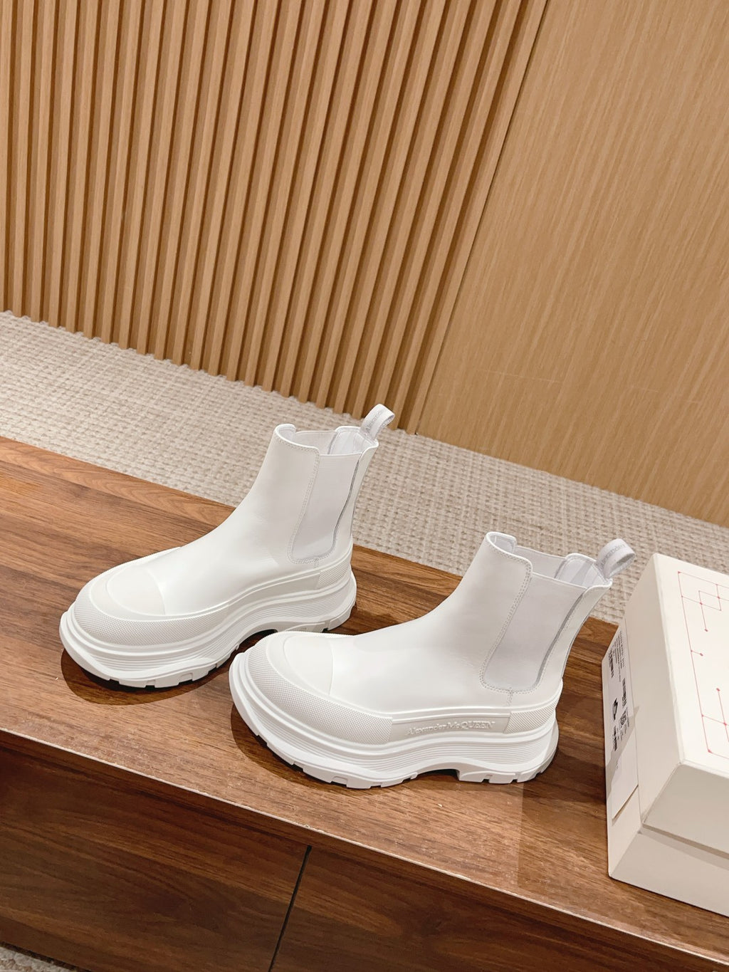 White Chelsea boots on display, slip-on ankle height with elastic gore and chunky sole