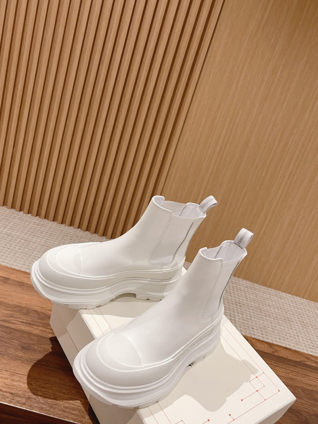 White Chelsea boots with elastic side panels and thick layered sole, angled view
