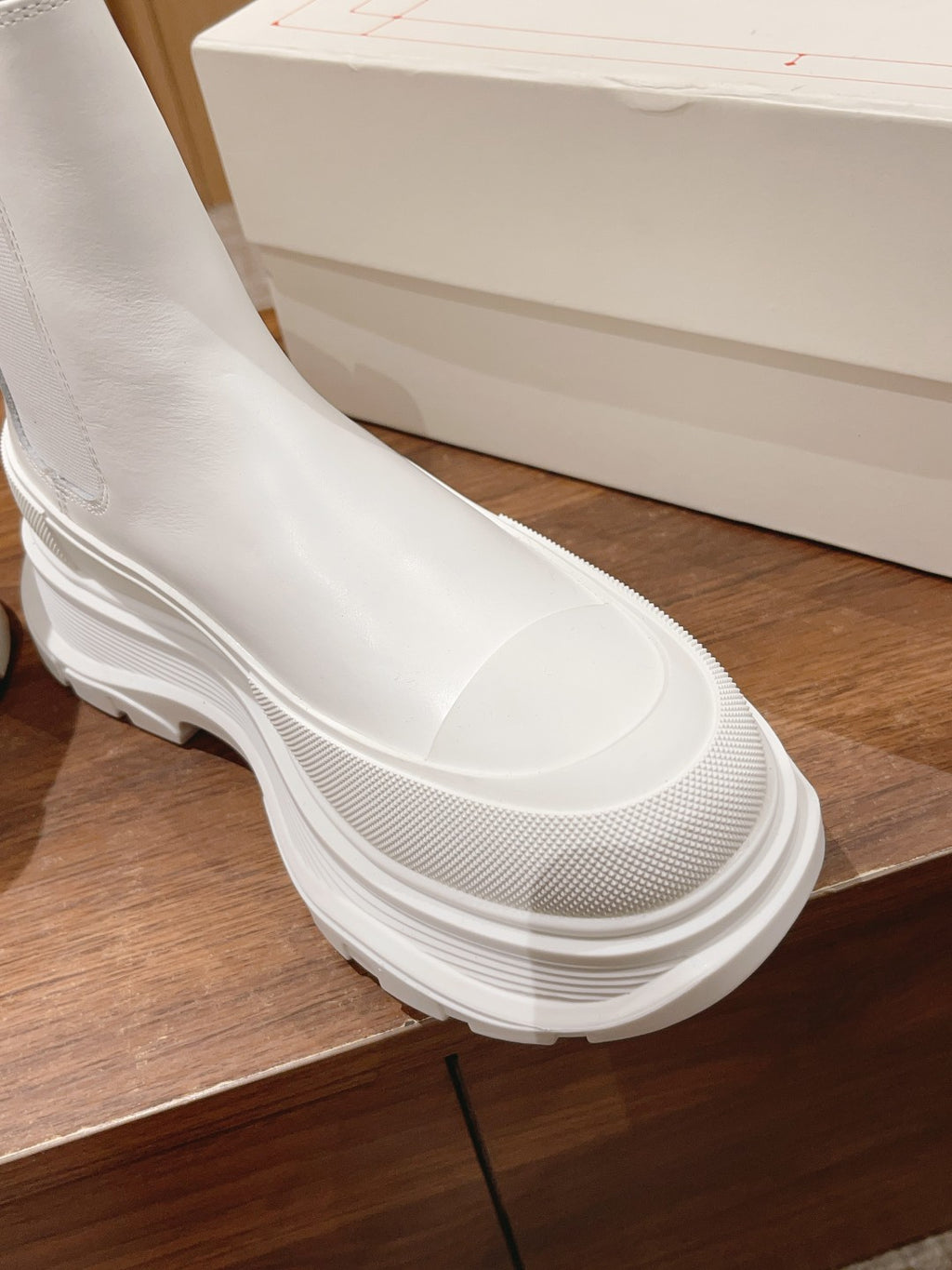 Close-up of a white Chelsea boot: smooth upper with textured inset and chunky sole