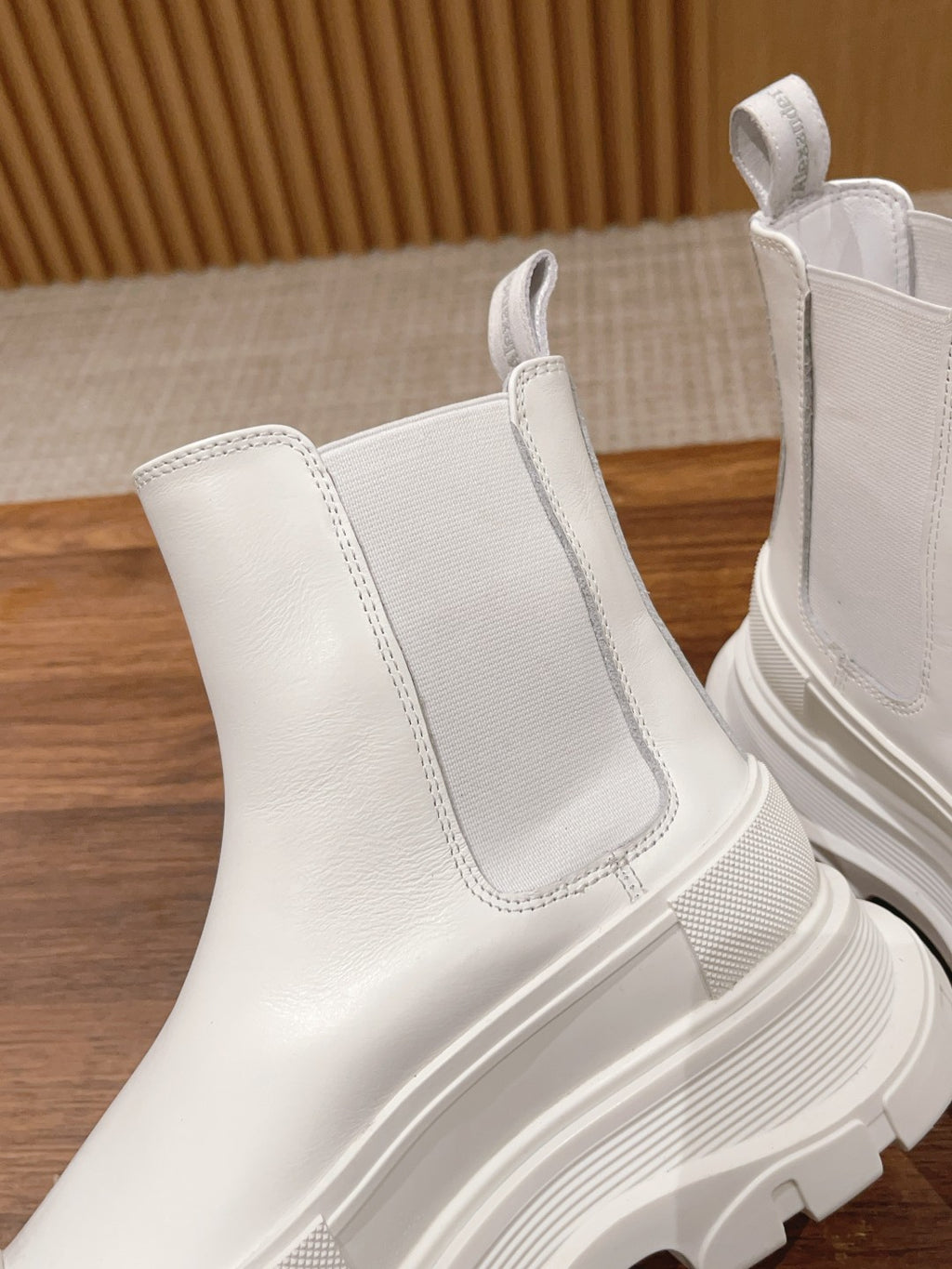 White Chelsea boot close-up with elastic gore and stitched side panels, chunky sole