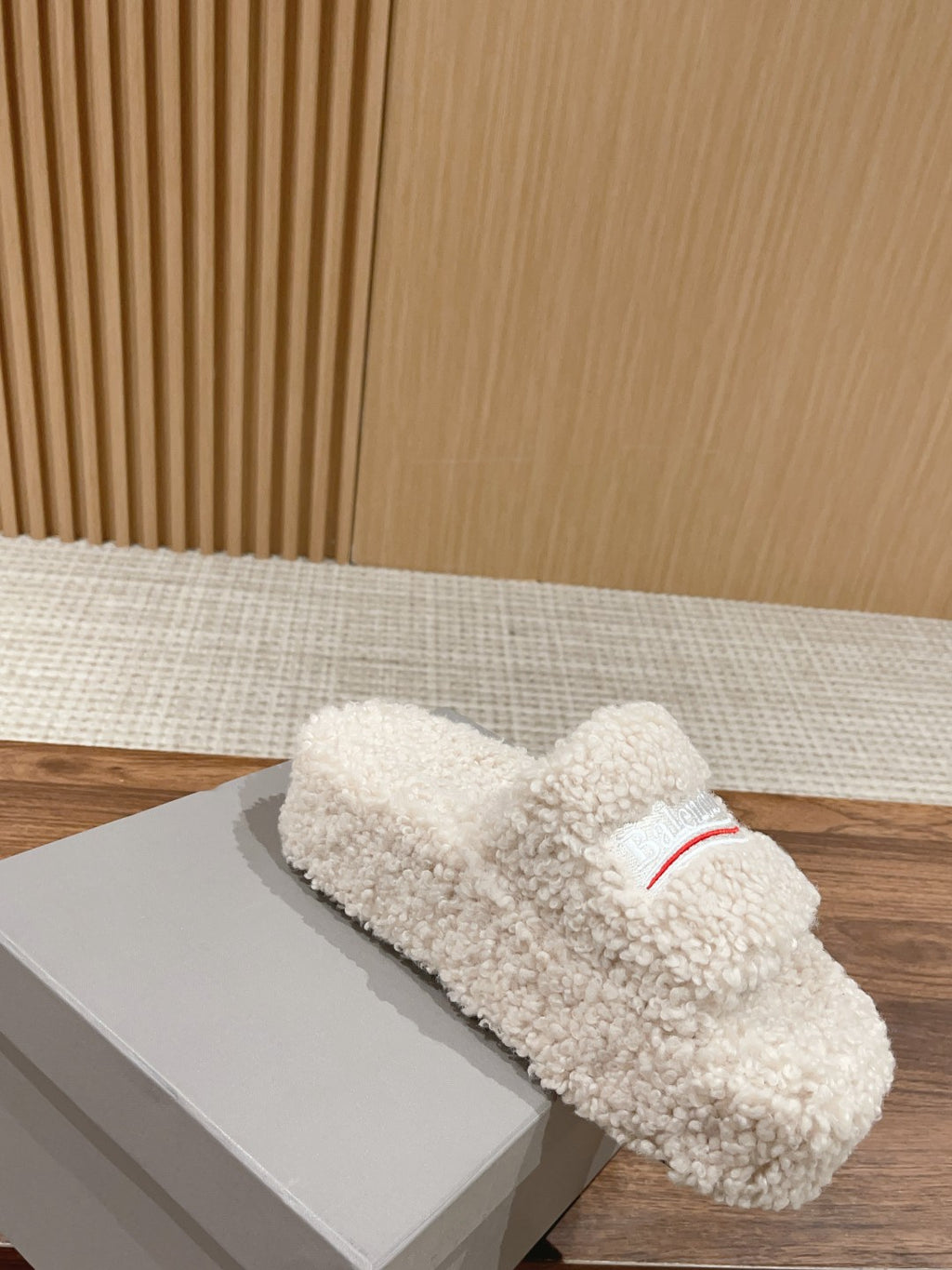 White shearling slide sandals with red logo stripe on the strap, side view
