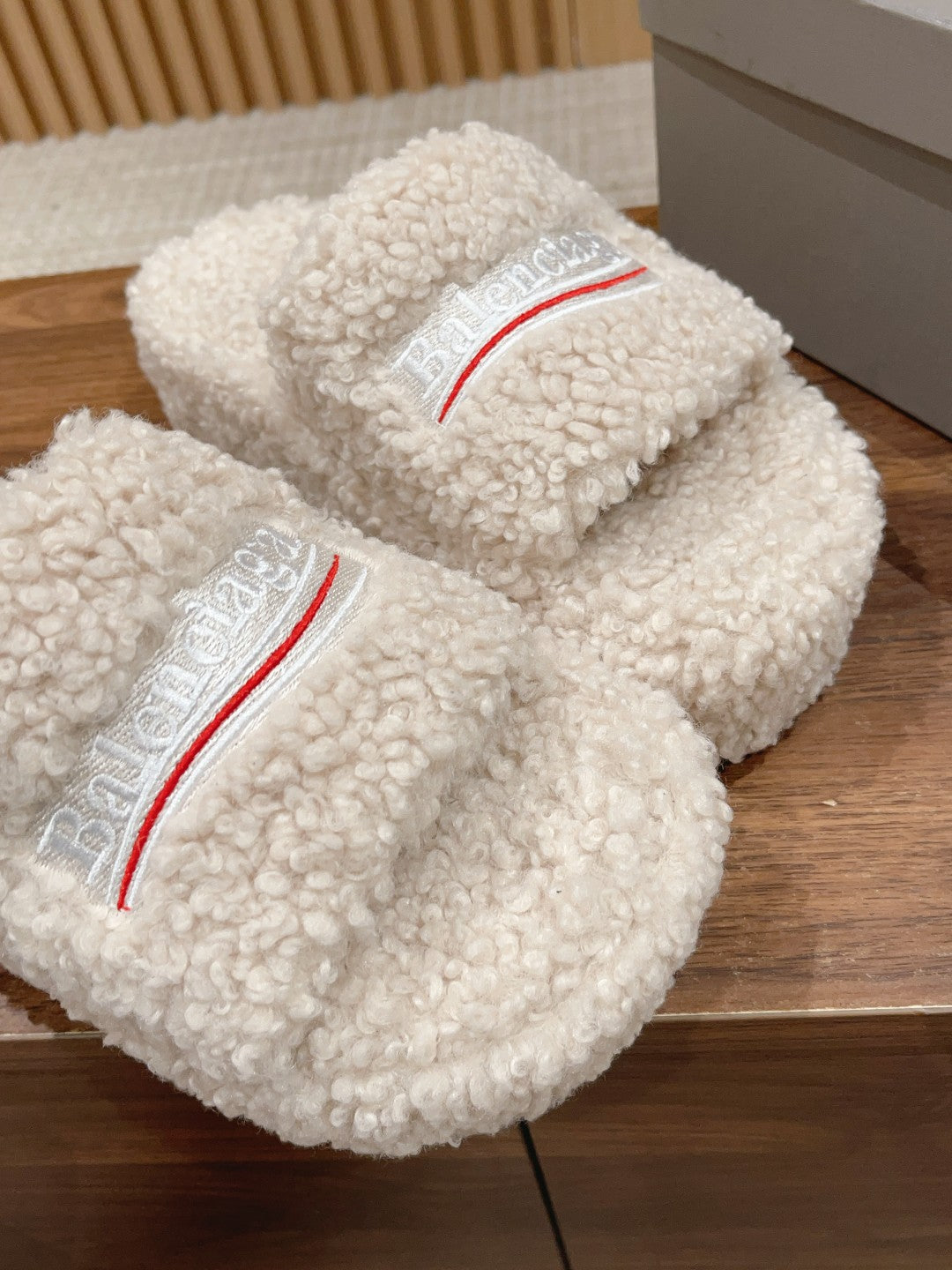 White shearling slides with red logo stripe and Balenciaga text on the insole