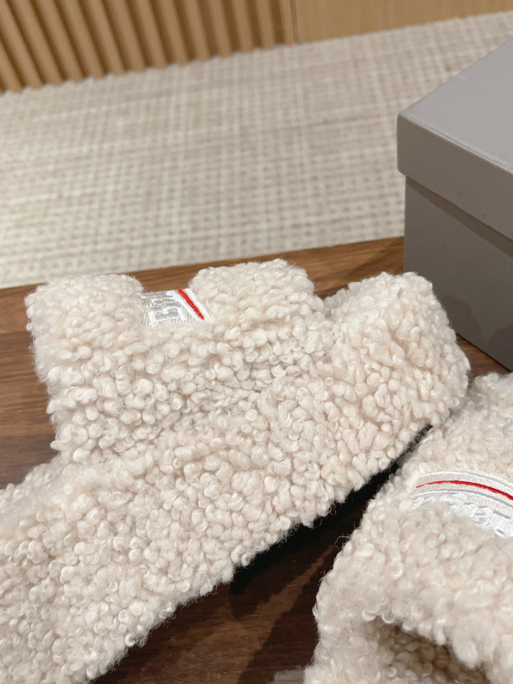 White shearling slide sandals showing the red logo stripe on the top strap