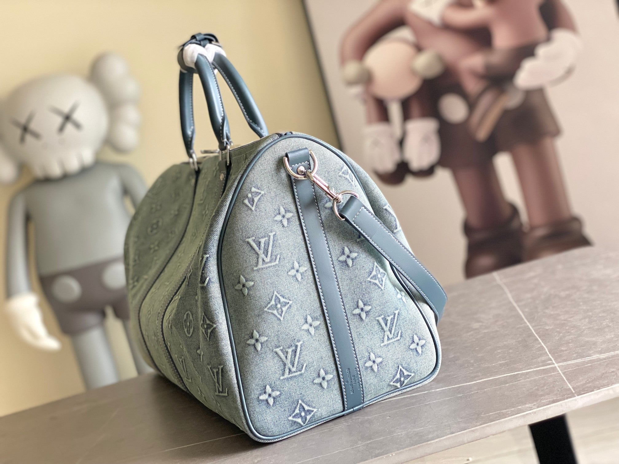 Louis Vuitton men’s bag, side view with top handle and blue monogram pattern