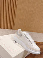 White Alexander McQueen sneaker on box, side view with studded trim