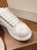 Close-up of white Alexander McQueen lace-up sneaker with metallic eyelets