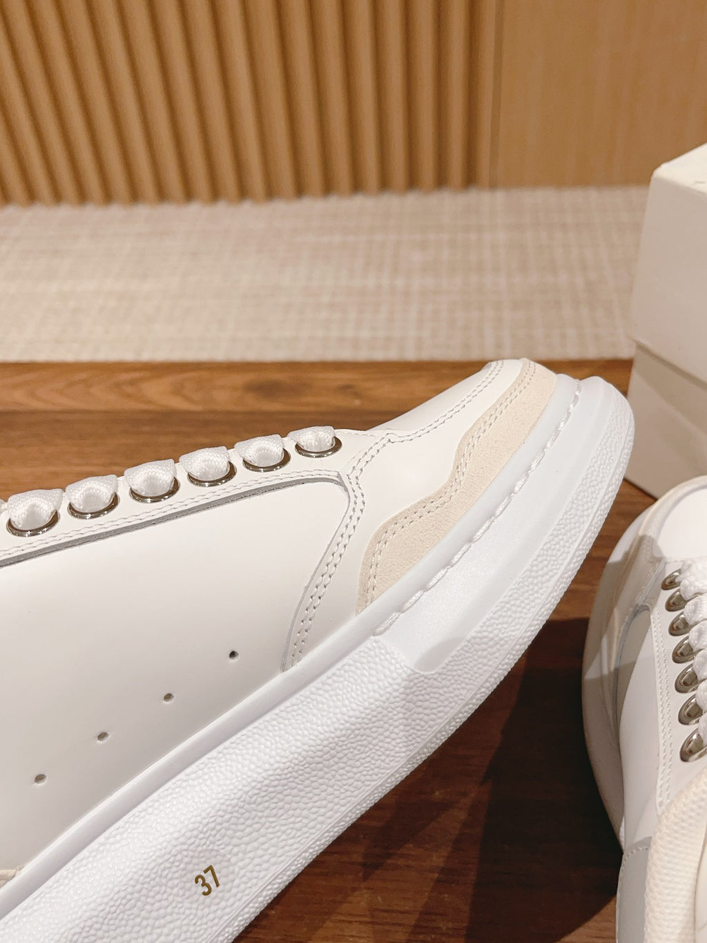 Close-up of white Alexander McQueen sneaker side with studded embellishments