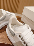 Close-up of white Alexander McQueen sneaker tongue and laces with logo patch
