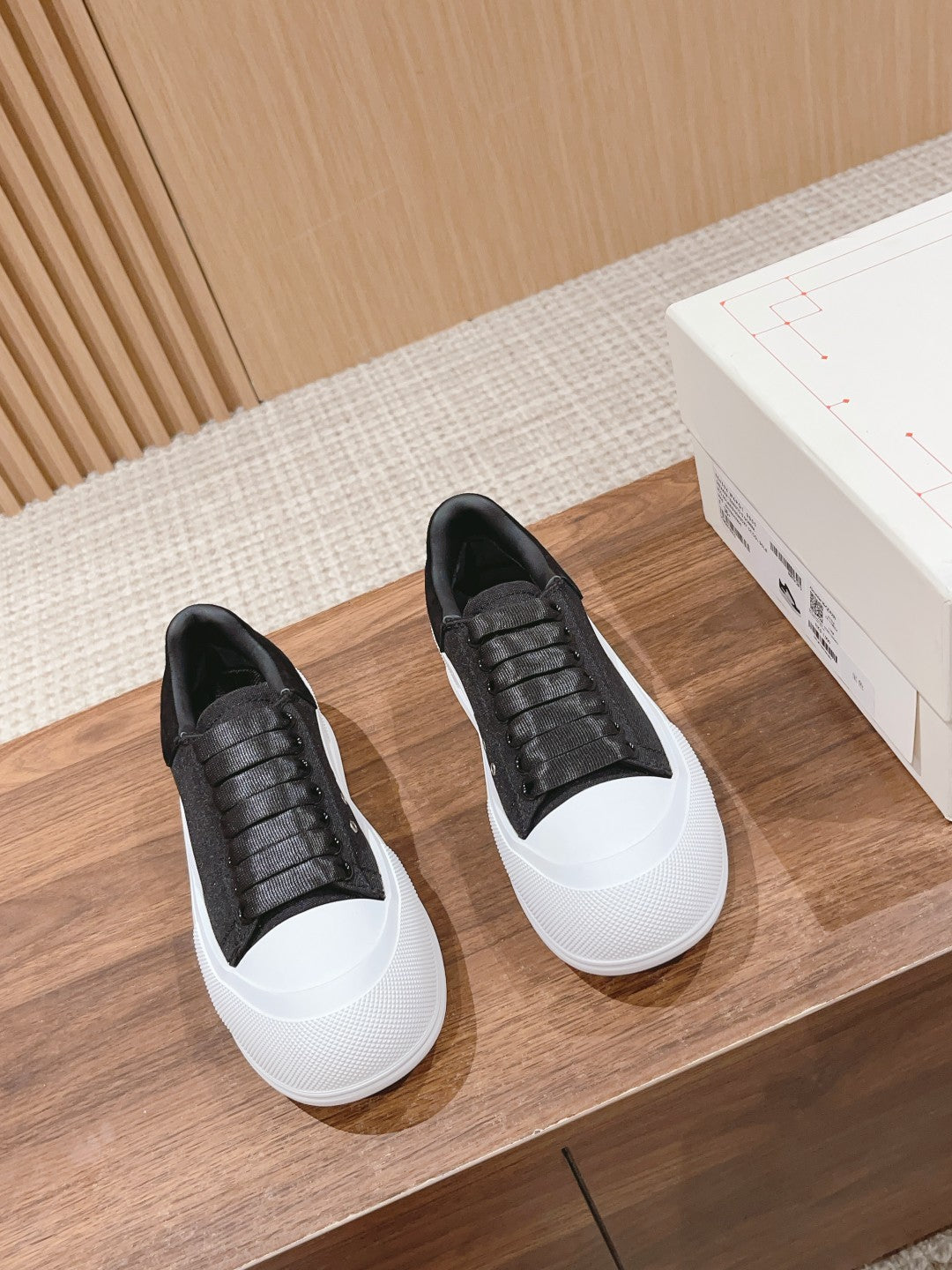 Pair of black sneakers with white soles and black upper laced with eyelets